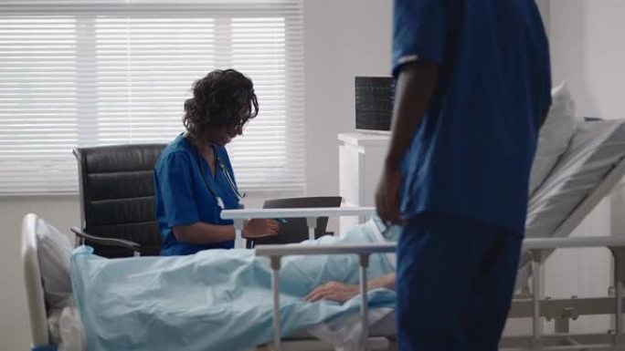 非洲年轻医生团队在医院卧床咨询新型冠状病毒肺炎感染患者。病人躺在医院的病床上，戴着磨砂膏和防护口罩与