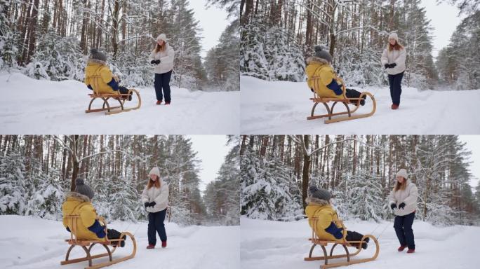 年轻的母亲和小儿子在冬天的森林里骑着雪橇，在高白雪皑皑的云杉之间行走