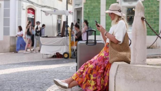一位旅行妇女提着手提箱在五彩广场休息