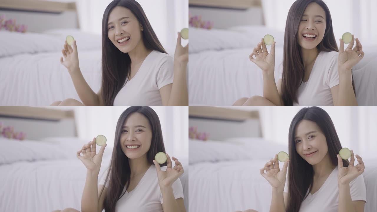 微笑的年轻女子在眼睛上拿着黄瓜片