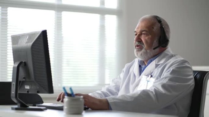 男医生坐在桌旁，使用笔记本电脑。穿着白大褂的男人坐在办公室里。
