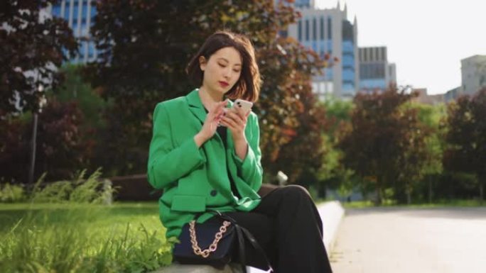 日本妇女在公园休息，使用智能手机，在线购物和观看社交媒体