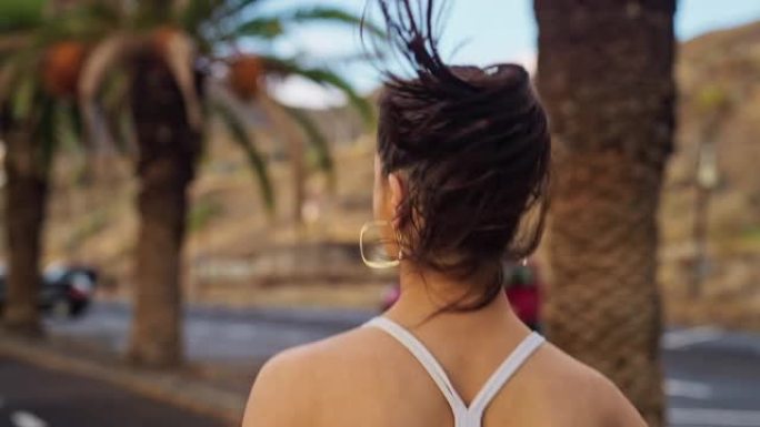 美丽的女人在地中海小镇慢跑。热带气候，后视图