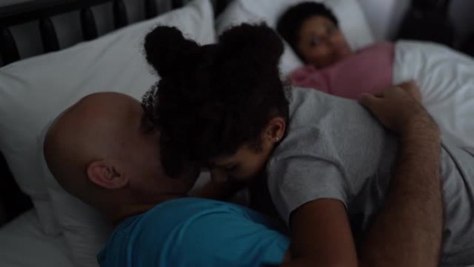床上的女孩与聋哑的父亲交谈并拥抱父母