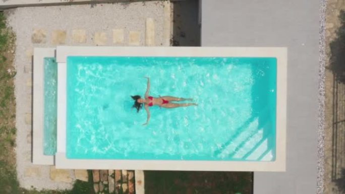 空中无人机拍摄了一名漂浮在游泳池中的妇女