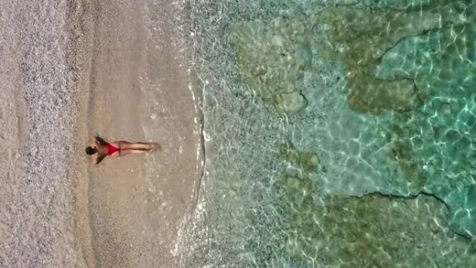空中无人机拍摄了一名妇女躺在水上海滩上的镜头