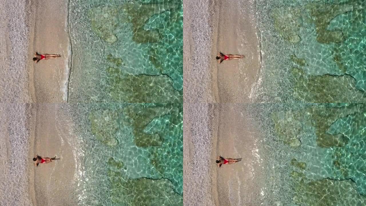 空中无人机拍摄了一名妇女躺在水上海滩上的镜头