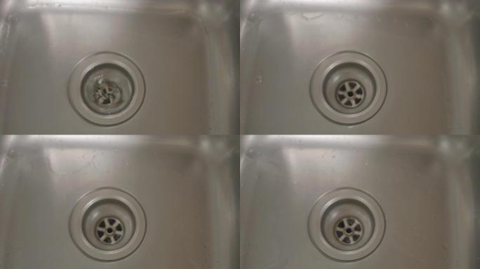 关闭上方锁定的水从不锈钢水槽的塞孔中旋转下来。在斯洛文尼亚拍摄。