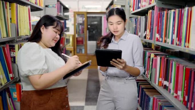 成人学生在图书馆用电脑讨论研究。