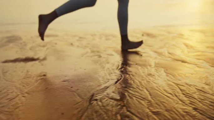 海滨慢跑训练。享受日落和自由的女人。赤脚在湿沙上奔跑