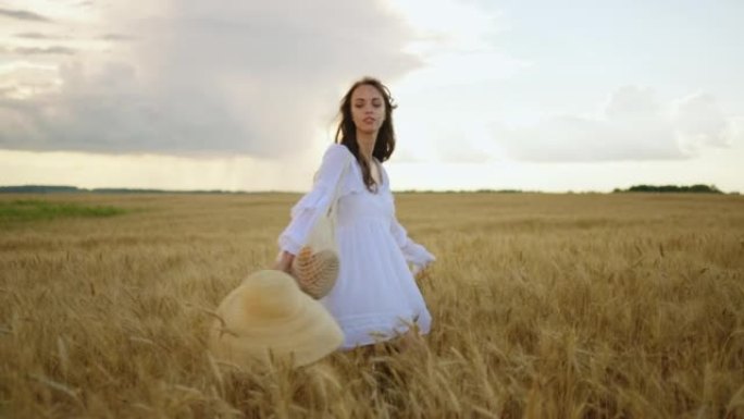 性感的年轻女子在夏日在成熟的麦田里旋转，享受大自然，抚摸成熟的耳朵