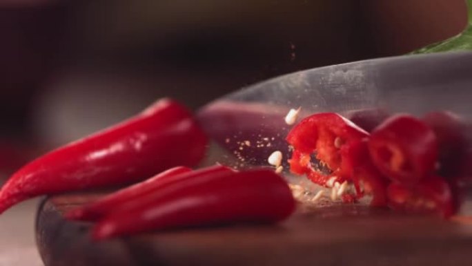 用刀在木头上慢动作切割红辣椒