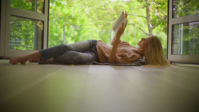 自爱时间。女人躺在开着的窗户旁，享受着书