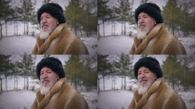 大胡子的土著老人望着远处，站在户外微笑着对着镜头。在白雪皑皑的寒冷日子里，老人在极地森林中慢动作的肖