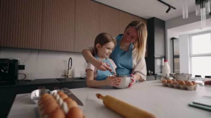 快乐的小女孩和她的木乃伊在一起做饭，母亲在教女儿做饭，一家人在家打发时间