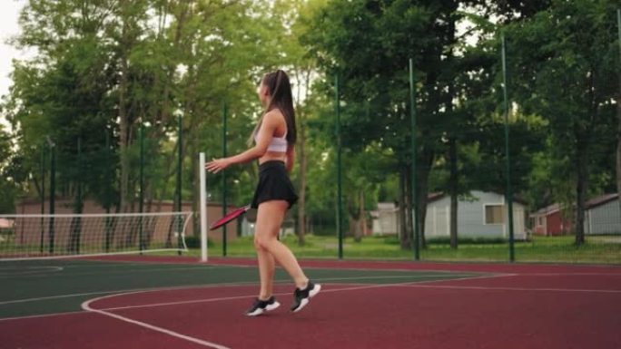 年轻苗条的女网球运动员正在公开球场上训练，运动的生活方式