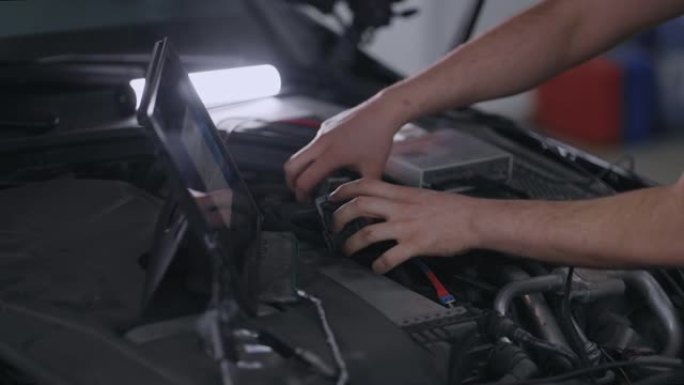 Hands Mechanic使用带有增强现实诊断软件的平板电脑。专家检查汽车以发现内部损坏的组件。男