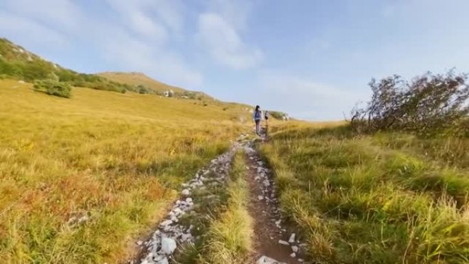 接近徒步旅行者在阳光下沿着山径行走