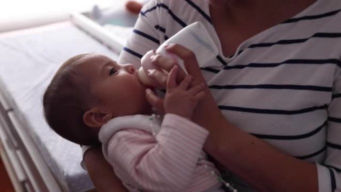无法辨认的母亲在喂养她时抱着一个带有髋关节发育不良支架的女婴的特写镜头