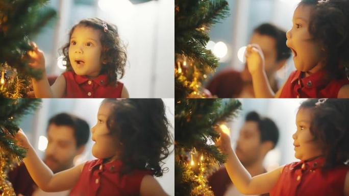 可爱的蹒跚学步的女孩和她的父亲在家里装饰圣诞树