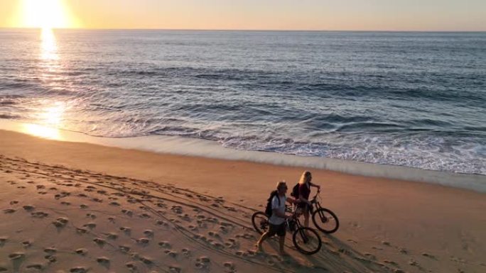 沿着海滩推自行车的夫妇的鸟瞰图
