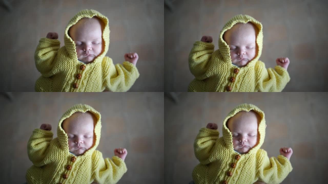 刚出生的婴儿穿着黄色手工毛衣睡在母亲的手中