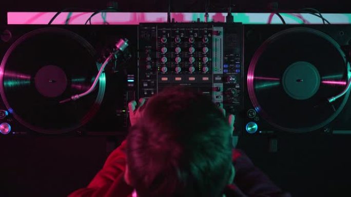俱乐部DJ在舞台上播放黑胶音乐。嘻哈唱片骑师用转盘和混音器混合音乐曲目的高架视频剪辑