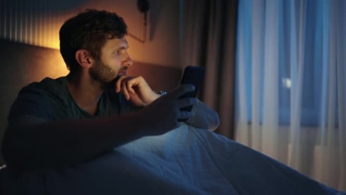 担心男人睡觉前在网上看新闻，床上拿着手机的男人的肖像