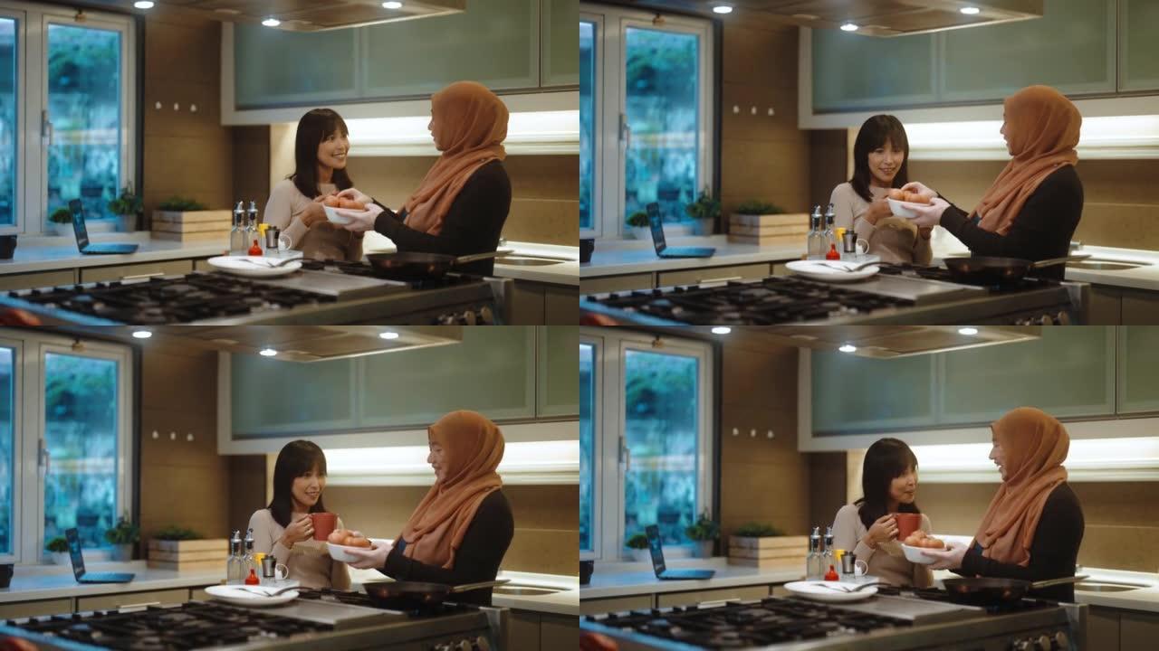 亚洲马来妇女白癜风皮肤状况在厨房准备早餐并与她的女性朋友交谈