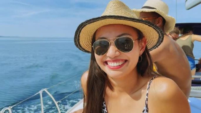 年轻女子在游艇上晒日光浴时对着镜头微笑