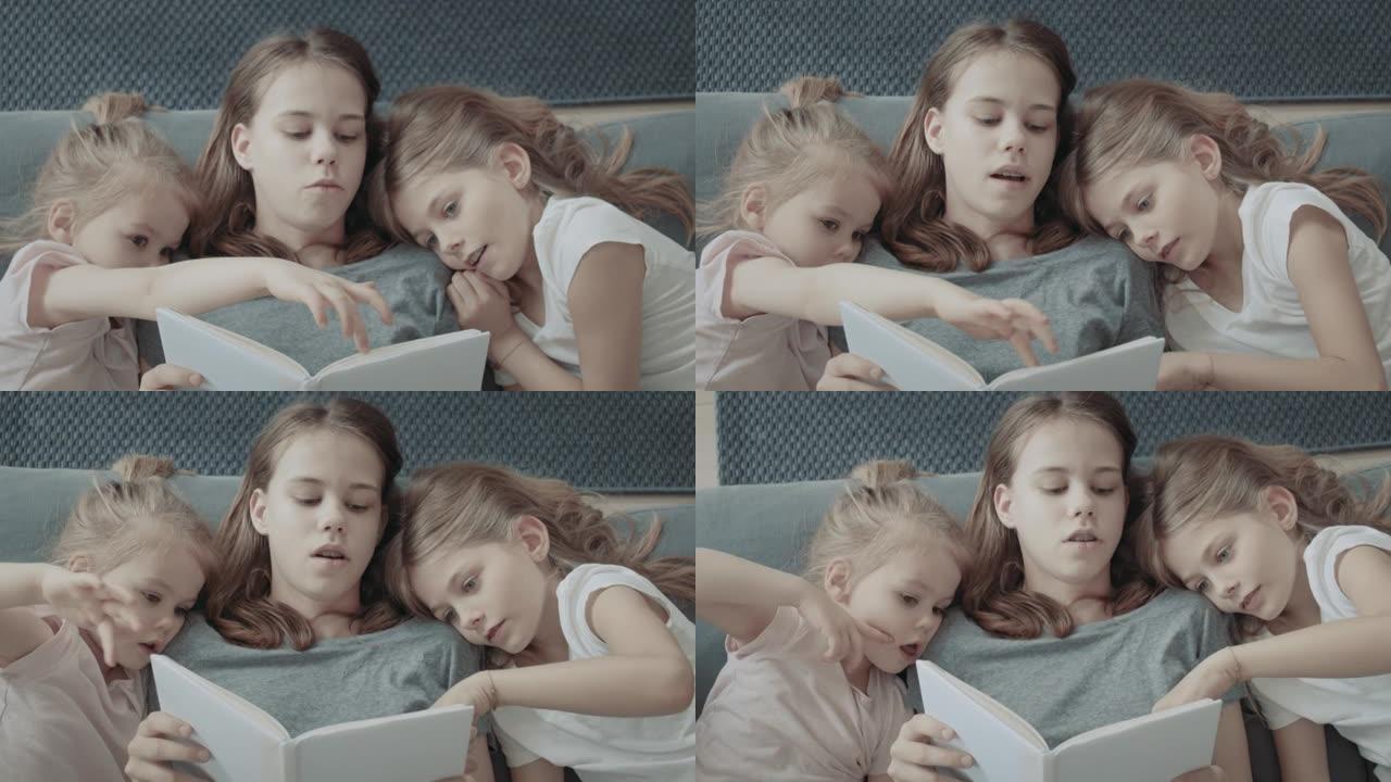 家庭阅读时间。三个小姐妹在沙发上看书，互相拥抱