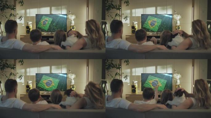 母亲父亲和两个孩子带着狗看电视。摄像机在屏幕上迅速向巴西国旗移动