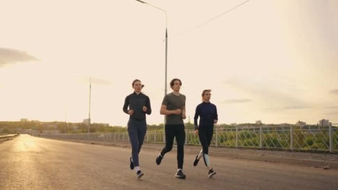 三名选手准备马拉松，两名女子和男子在日落或日出时慢跑