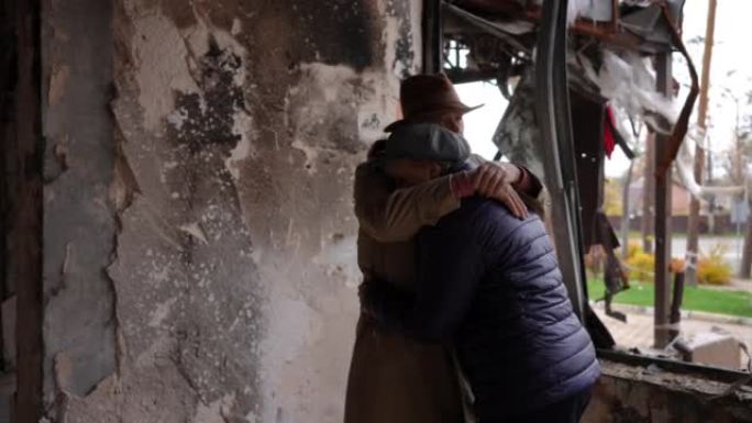 拥抱悲伤的老夫妇站在被战争摧毁的建筑里思考。在被炸毁的乌克兰城市，绝望绝望的男人和女人在废墟中的画像