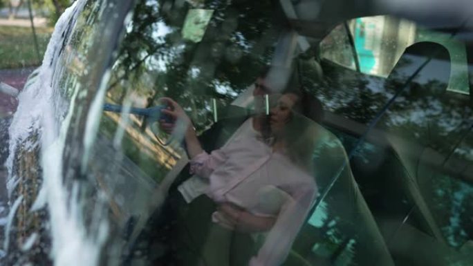 黑色豪华洗车慢动作与年轻夫妇清洁车的反射。成功自信的高加索男人和女人拥抱在车窗里倒影。