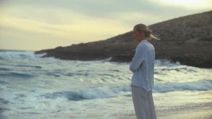 独自站在海滩上的女人。望向遥远的大海，享受微风