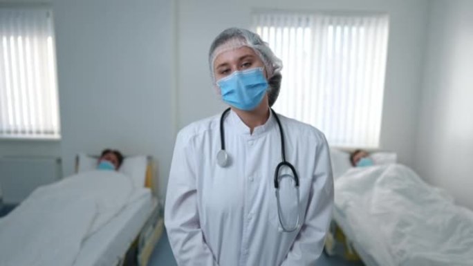 疲惫的护士戴着冠状病毒口罩，回头看病人摇头，看着相机叹息。在医院病房摆姿势的疲惫悲伤的高加索妇女的中