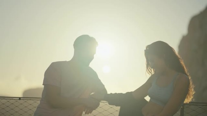 热爱旅游的浪漫情侣在日落时拥抱和亲吻双手