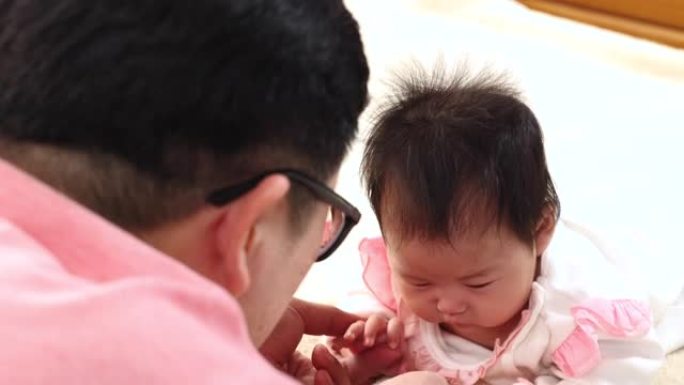 亚洲特写爸爸与健康新生儿眼神交流3个月充满爱与幸福，父亲与可爱的女儿在床上玩耍，蹒跚学步的婴儿新生儿