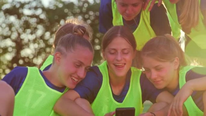 女子足球队在智能手机上观看视频并在练习后大笑