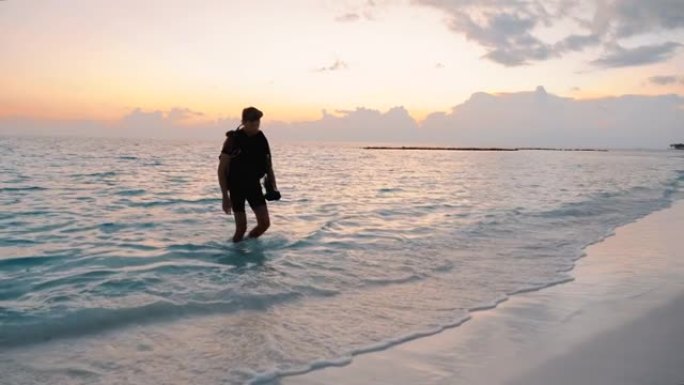 潜水员在日落时走出大海来到海滩