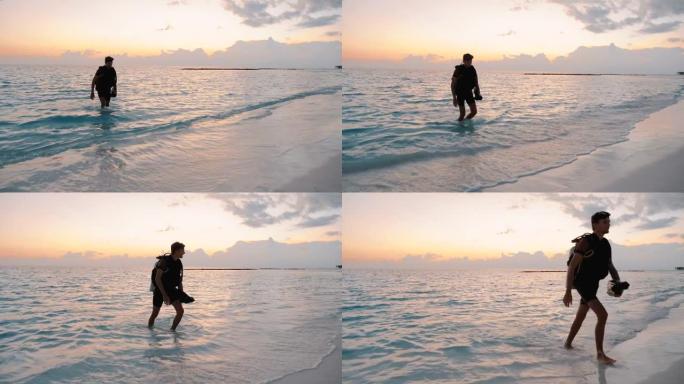 潜水员在日落时走出大海来到海滩