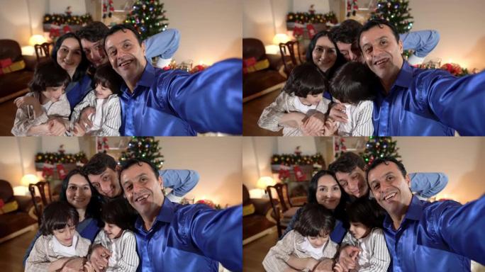 自拍POV快乐中东男子在平安夜在家室内与家人合影。微笑的男人与白人女子少年和双胞胎兄弟一起享受新年庆