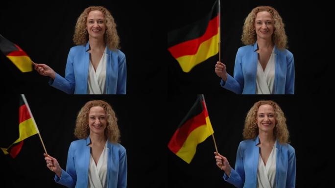 自信微笑优雅的女人飘扬着德国国旗看着相机在黑色背景闪光灯。政客拿着国旗在新闻发布会上摆姿势。运动和简