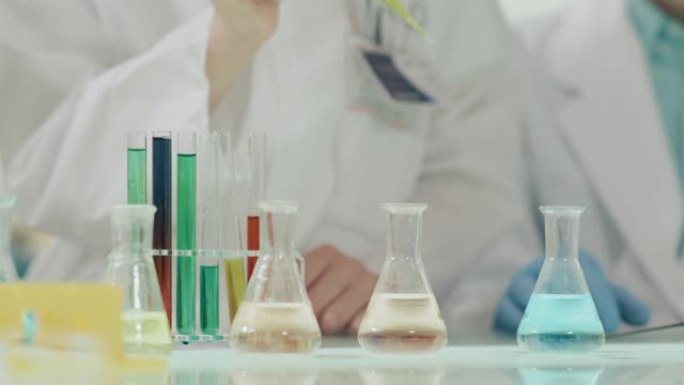 孩子们进行科学实验。实验室内部，用移液管倒多色液体。双手合十