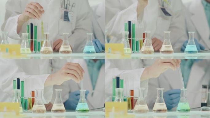 孩子们进行科学实验。实验室内部，用移液管倒多色液体。双手合十