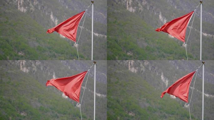 红色海滩警告标志的详细镜头在后面的山上吹动
