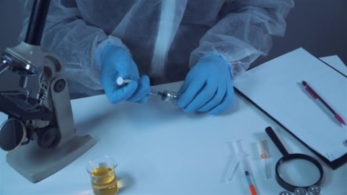 一名穿着防护服的实验室技术人员拿着一小瓶冠状病毒疫苗，并拿着注射器液体。科学家在实验室。冠状病毒疫苗