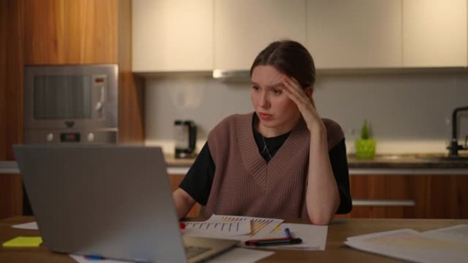 一个沉思的女人在家工作时看着电脑显示器。创造发明。解决问题和集思广益