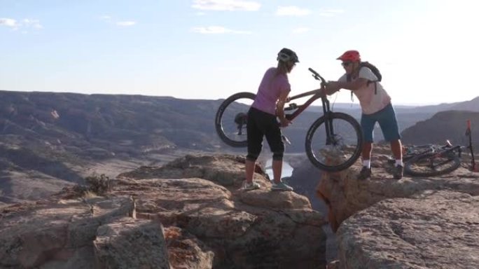 山地车手为峡谷俯瞰的女性同伴提供帮助